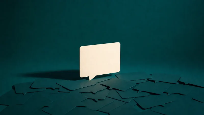 A pale paper speech bubble standing on a deep teal surface scattered with fragments, the cover for the course Get Found by AI Search